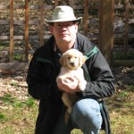 Man in Hat Holding Golden Retriever Puppy