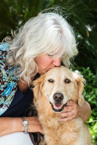 Pam kisses Honey the golden retriever on the head in a professional photograph.