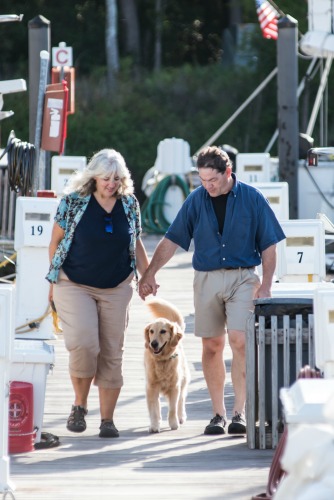 Pam and Mike holding hands with Honey the golden retriever.