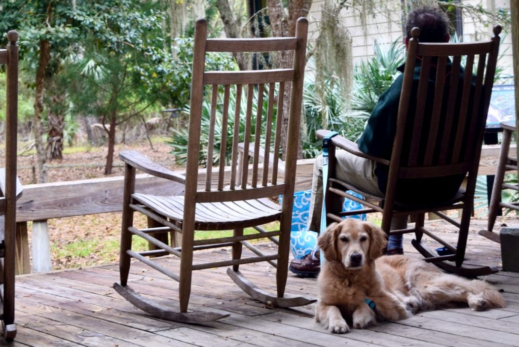 A favorite dog-friendly anchorage on the ICW? Edisto Island State Park. (Golden retriever lying on a porch behind man in a rocking chair.)